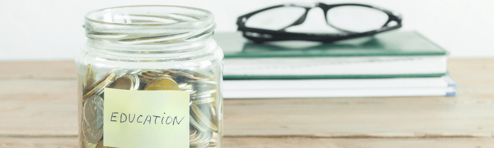 jar of coins with label that says education in front of books with glasses on top of them