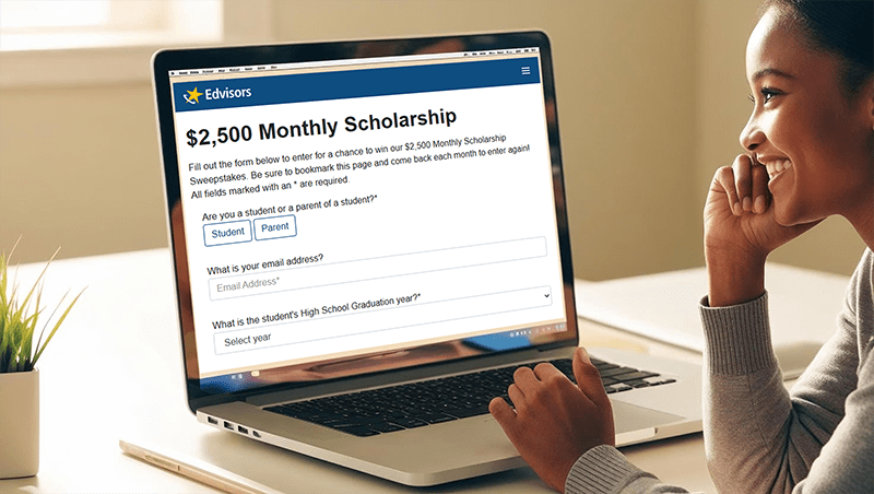 Smiling girl enters the Edvisors $2,500 Scholarship on Laptop