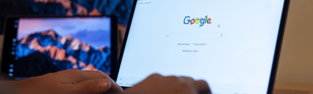 hands typing on laptop showing google home page
