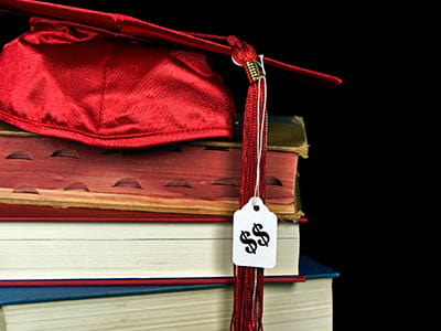 Graduation cap with price tag sitting atop textbooks