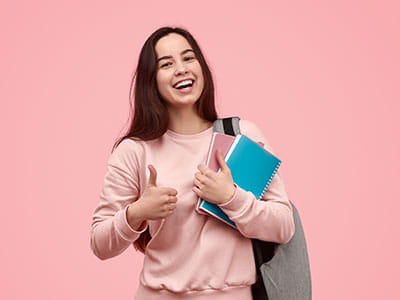 Female college student holding books making a thumbs up sign