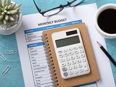 Printed monthly budget on table with calculator and notepad all ready for review