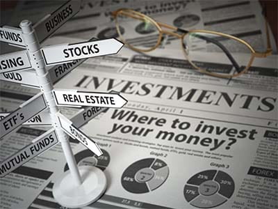 Investments - Newspaper on investment section with sign sitting atop with options: stocks, real estate, eft's, mutual funds
