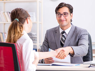 Man and women shaking hands at a desk in agreement