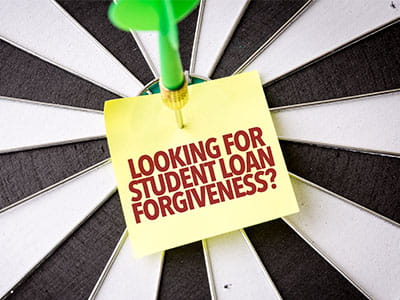 Dart board with dart in bullseye piercing note saying looking for student loan forgiveness