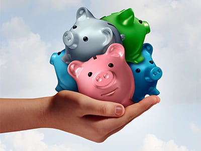hand holding bundle of 4 mini piggy banks to convey concept of refinancing student loans into a consolidation loan