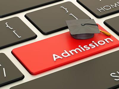 Keyboard with red key saying admissions with graduation cap  to convey concept of college admissions