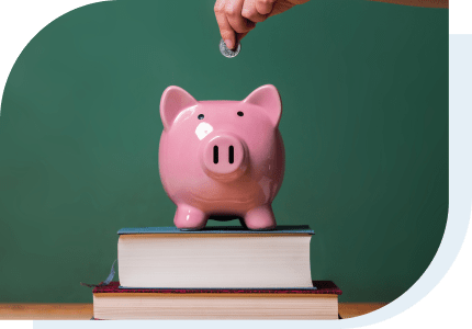 piggy bank on a stack of books with a hand putting a coin in it to help pay for college